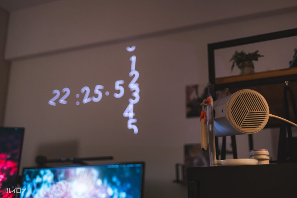 デスク奥の壁へ壁時計を投写している様子